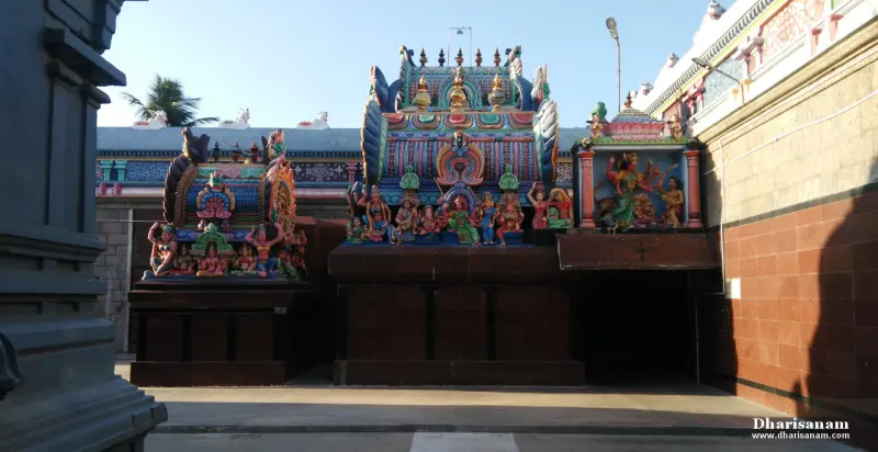 Colourful sculpted shrine roofs on top of a brown stone base, with a stone pillar at the left.