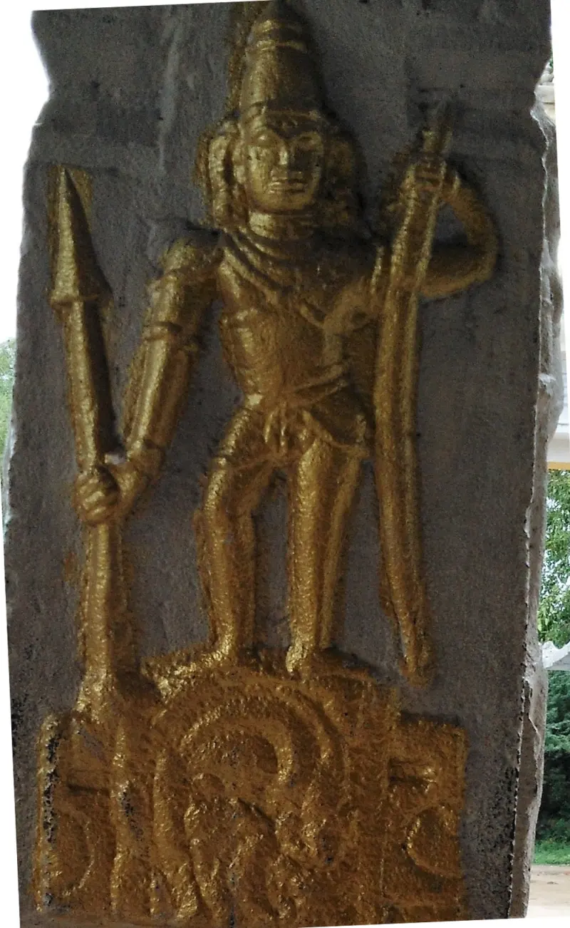 Golden standing figure holding a long bow, carved on a stone pillar
