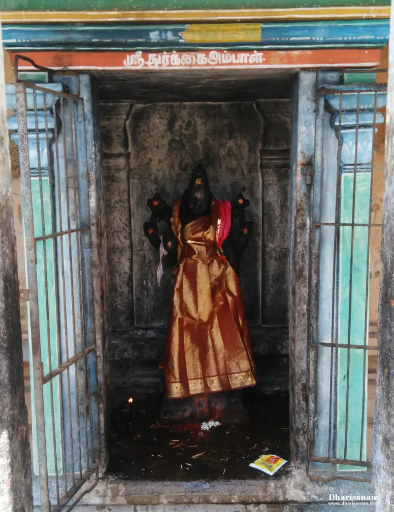 A small shrine with a goddess image in a gold-orange silk, behind iron bars, under a Tamil name board