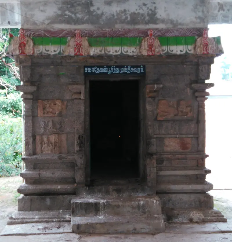 A small stone shrine with a Tamil board above the door