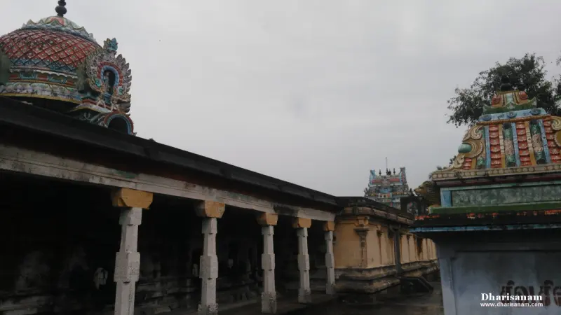 Row of white stone pillars along a corridor, with painted shrine roofs and a distant tower