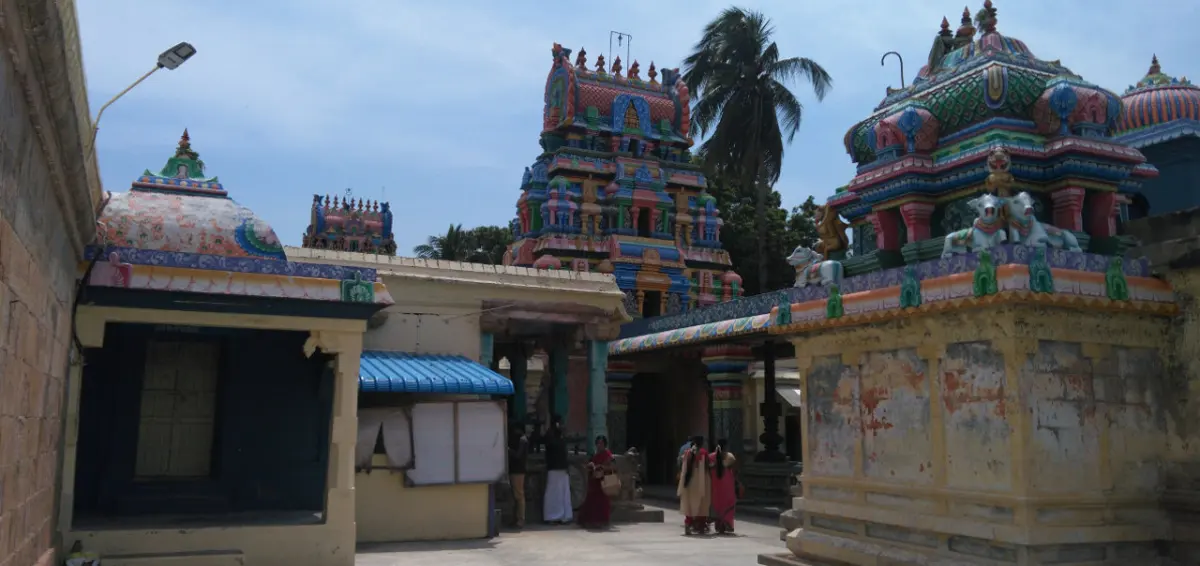 Colourful temple towers and shrine roofs above a courtyard, with devotees walking below