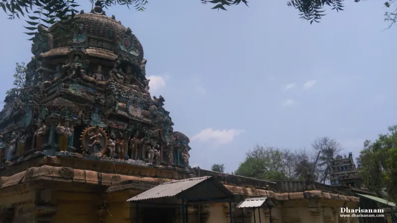 A tiered tower covered in painted figures and a wheel motif, under a blue sky.
