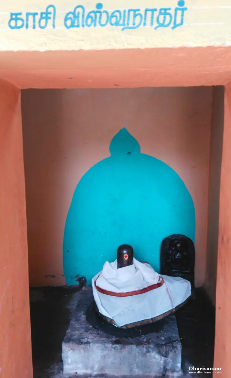 A black lingam wrapped in white cloth in a small shrine, with a Tamil name board above and a small relief beside it