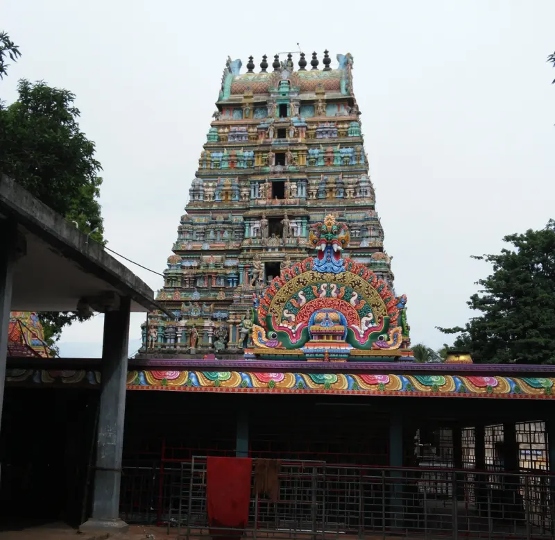 A tall tiered gateway tower covered in colourful figures, with a large decorated arch below it.