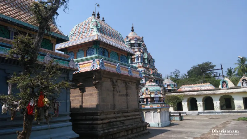 A painted shrine roof beside a tree hung with cloth offerings, with a tower behind it