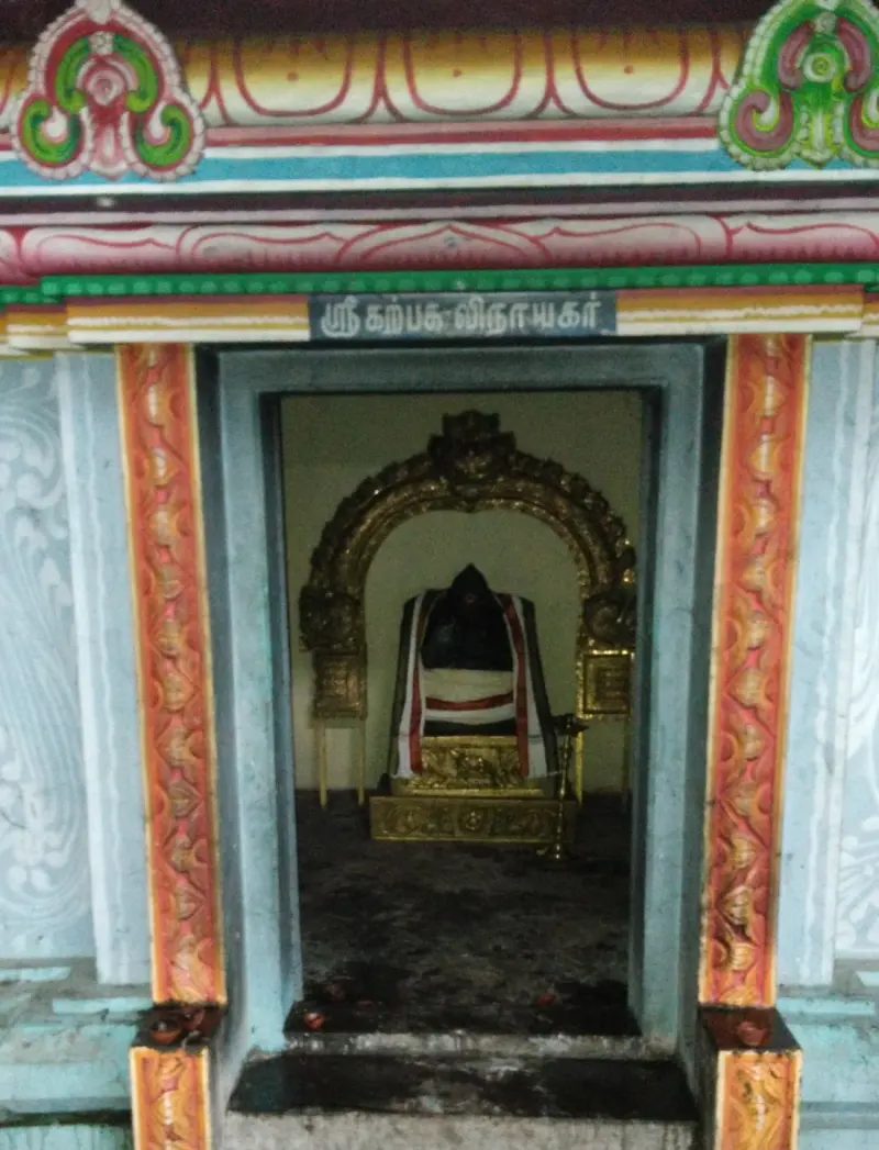 A small shrine with a dark Ganesha idol in cloth before a gilded arch; a Tamil board names Karpaga Vinayakar.