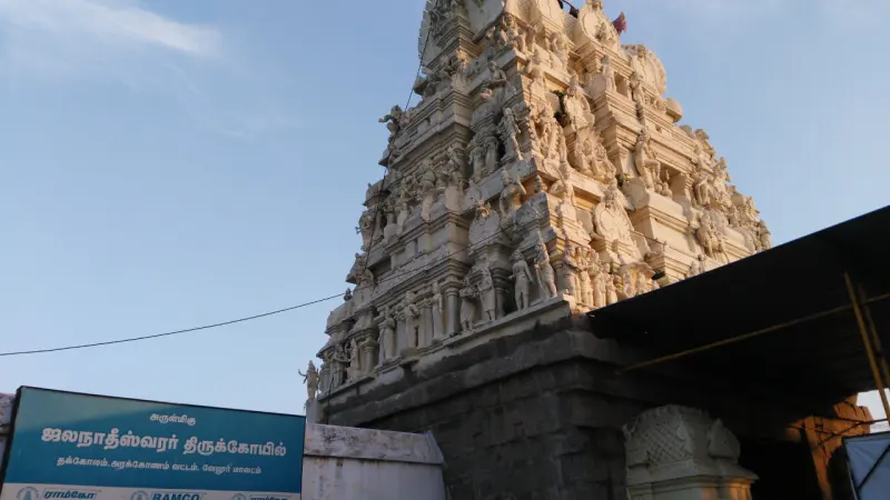 A tall white sculpted tower above a blue Tamil name board