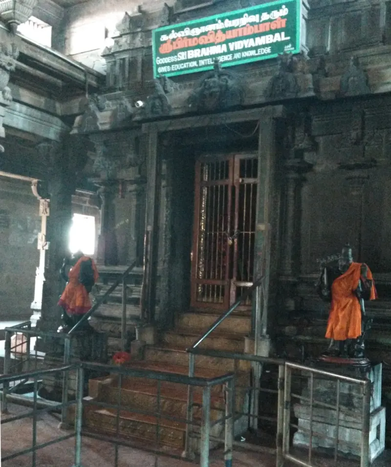 Steps up to a shrine doorway with a green signboard naming Goddess Sri Brahma Vidyambal, guarded by two figures