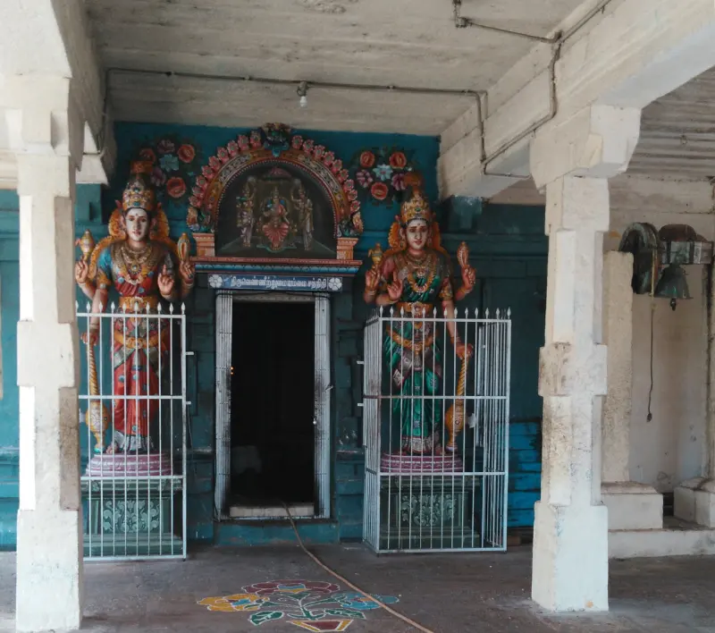 Two painted guardian figures behind iron grilles on either side of a dark doorway