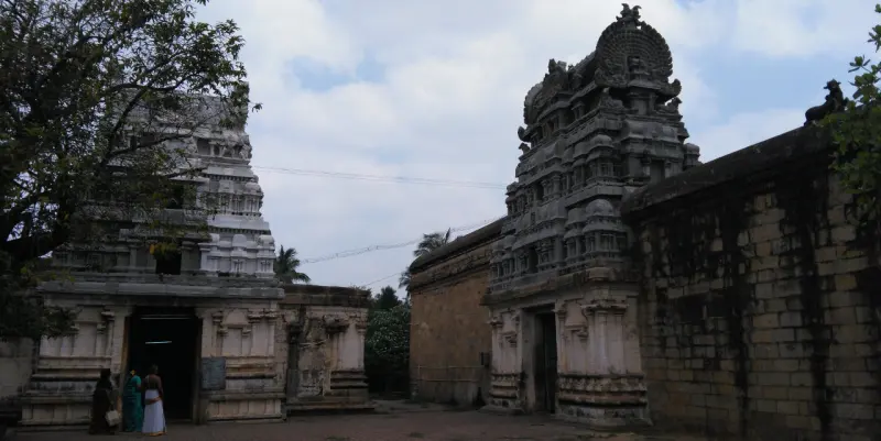 Two stone gateway towers with carved bases; visitors stand at the doorway of the left one.
