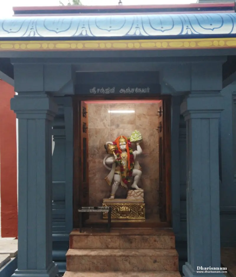 A white marble Anjaneyar carrying a mountain, in a small blue pillared shrine with steps in front