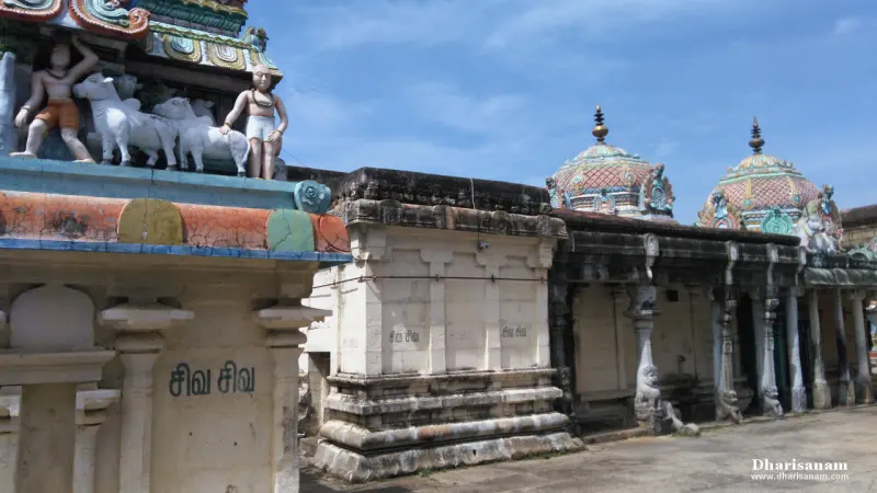 Colourful domed shrine roofs with sculpted figures, and a tower beyond, under a blue sky