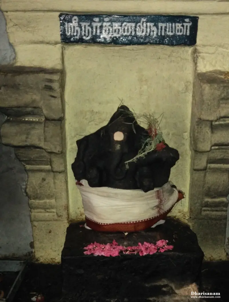 Dark dancing Ganesha idol in white cloth under a Tamil name board