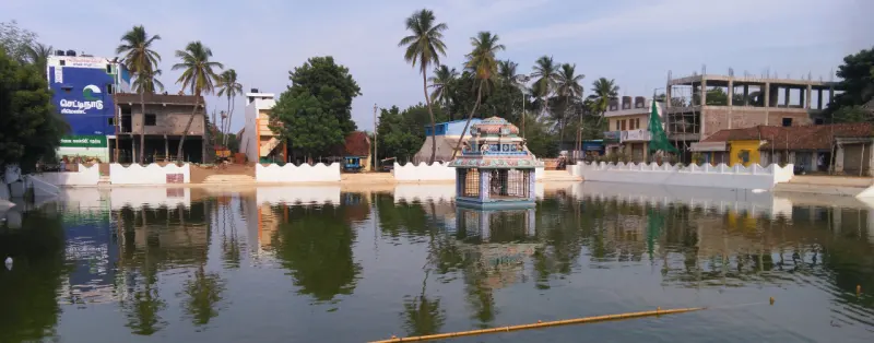 The temple tank and its central mandapam, with palms behind