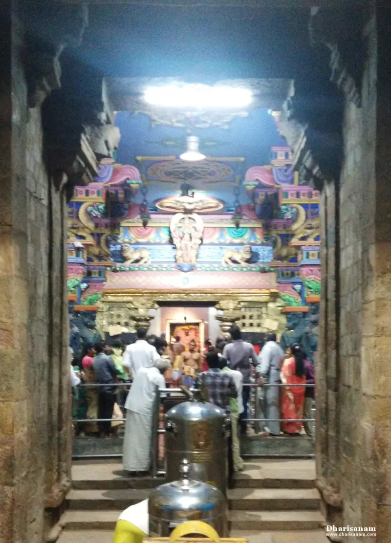 Devotees queue on steps before a brightly painted shrine entrance seen through a stone doorway
