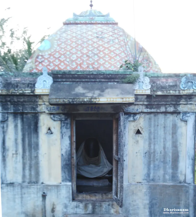 Small stone shrine with a patterned dome and an open door showing a lingam under a cloth