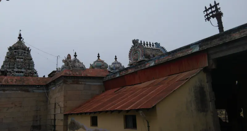 Several small towers and a tiled roof inside the temple compound, with a flagstaff beside them.