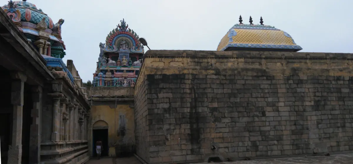A long stone wall with a domed roof and two towers rising behind it, seen from the corridor