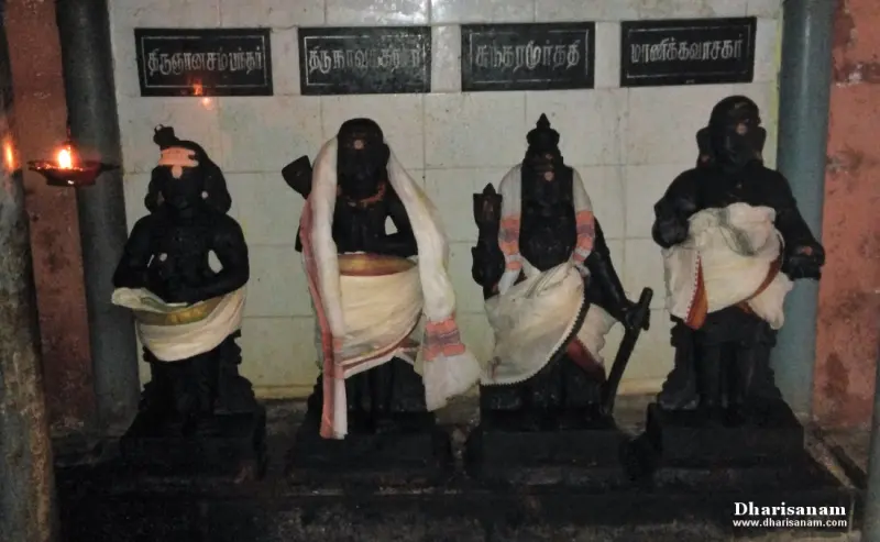Four dark idols in a row, each draped in white cloth, with Tamil name boards above.