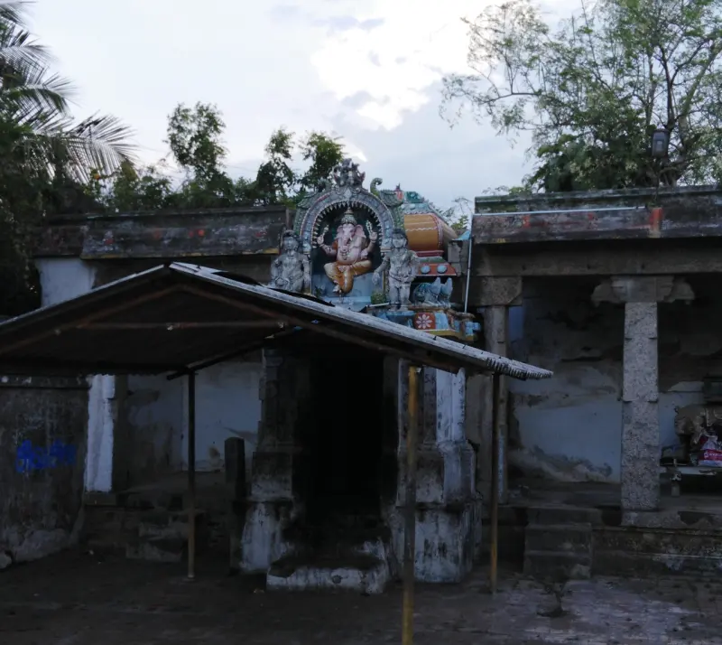 Small shrine with a painted seated Ganesha above, and a shed roof in front