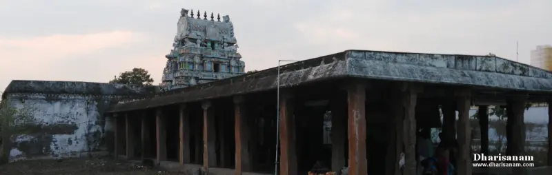A small painted tower rising behind a long pillared hall with a sloping roof