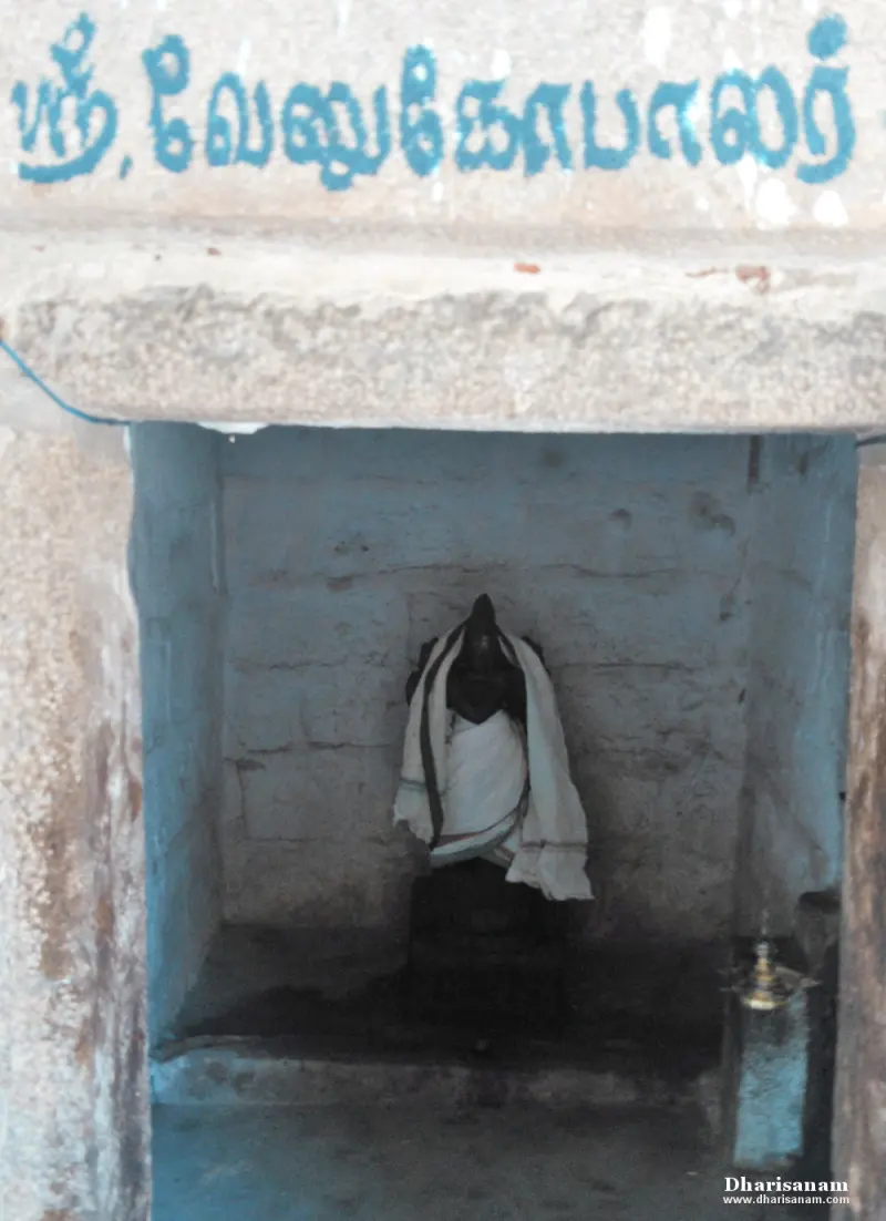 A small niche with a dark idol in a white cloth, with Sri Venugopalar written above in blue