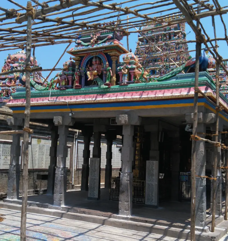 A stone porch with plain pillars and a painted roof, covered by a lattice of bamboo scaffolding.