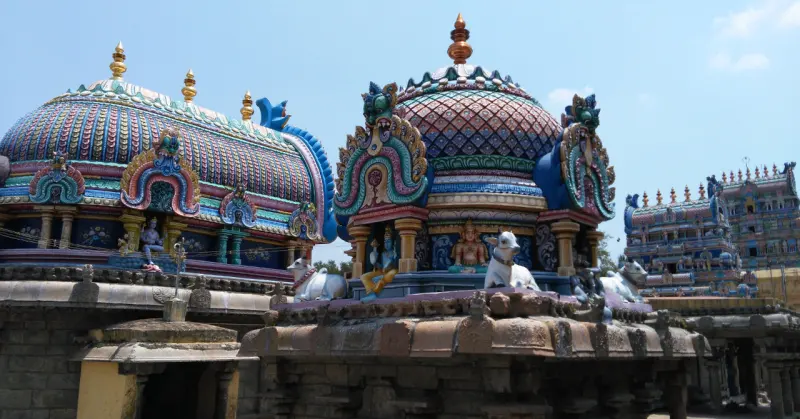 Painted domes with white bull statues beside a rear-shaped apsidal roof, above a stone corridor