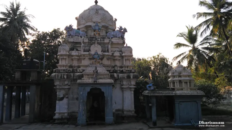A white tower with painted figures and bulls, a blue-framed entrance below and palm trees on the right