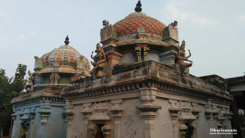 Two colourful domed shrine roofs with sculpted figures at the corners, against a pale sky
