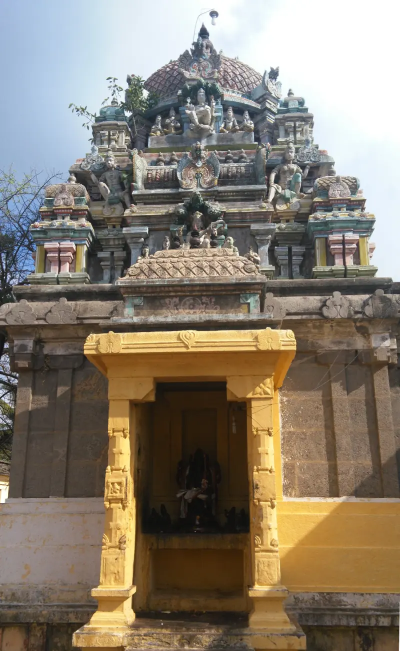 A yellow-framed shrine entrance beneath a tower of painted stucco figures