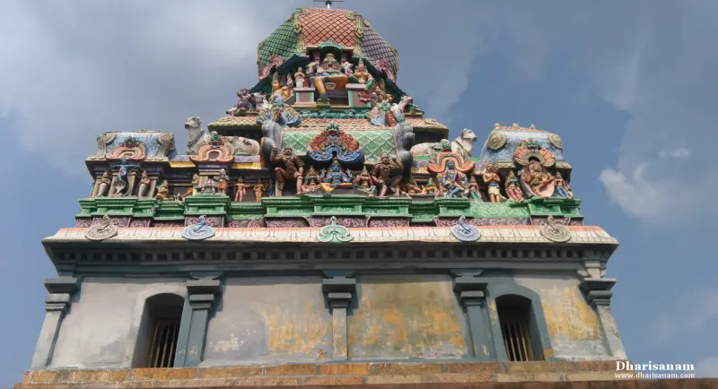 A shrine roof with rows of painted figures and bulls on top of a plain wall with two barred windows