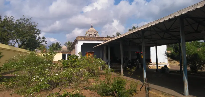 White temple buildings with a small domed tower, jasmine bushes in the foreground