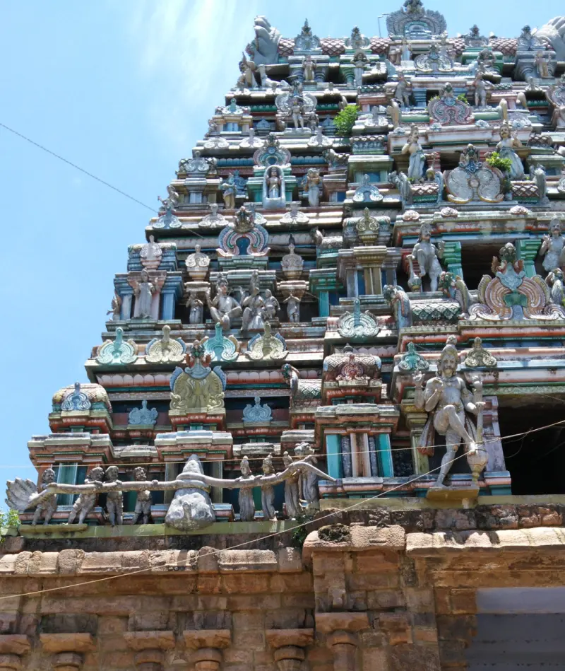 Close view of the tiers of a tower covered in painted figures, with a large standing figure at lower right.
