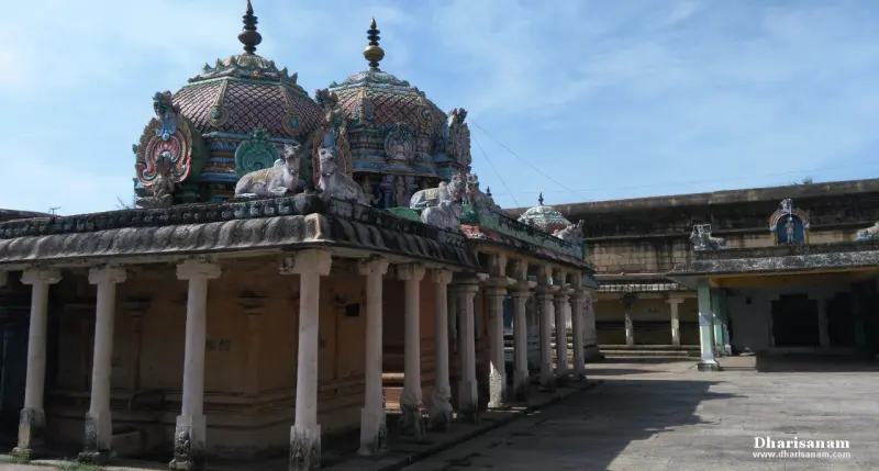 Two domed shrine roofs topped with finials and bull figures, above a pillared hall