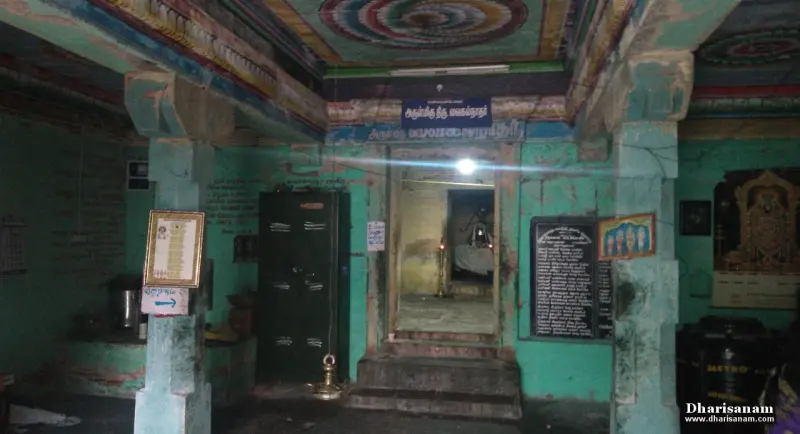 A green-walled hall with painted ceiling, a lit doorway ahead with steps, and a black notice board at right.