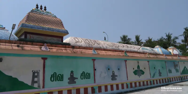 A long green and white wall painted with lingam outlines and the word Shiva in Tamil, below a domed roof