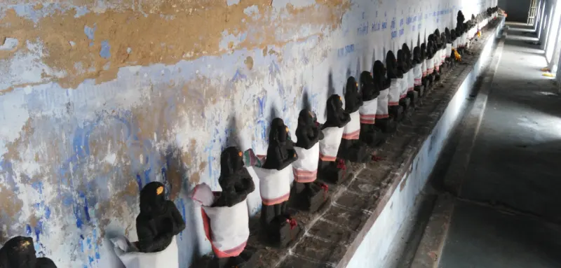 Long row of small draped idols along a weathered wall