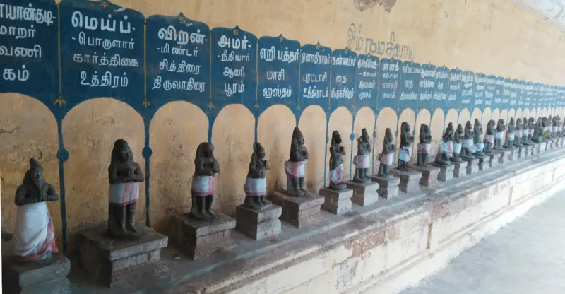 A long row of small draped idols with Tamil name boards above