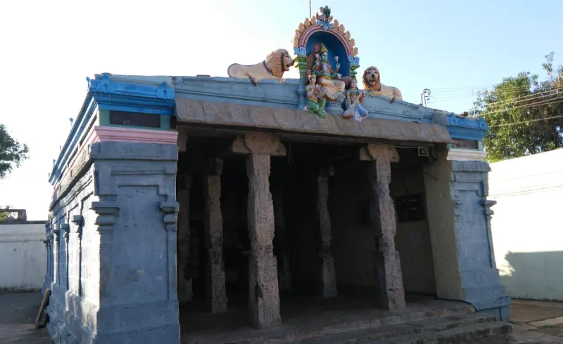 An open hall with carved stone pillars, with two lion figures and a small group of figures on its roof