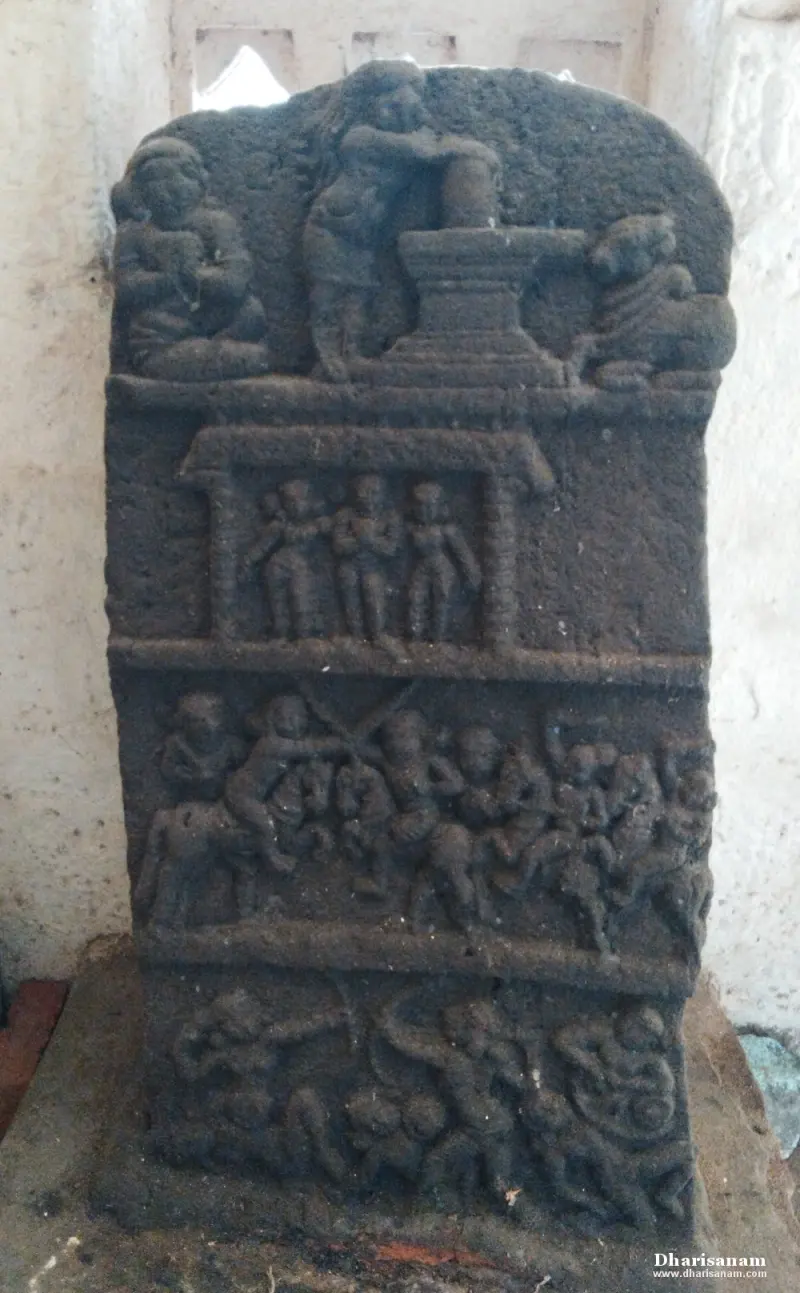 A tall stone panel carved in tiers: a figure worshiping a lingam above, then a group scene and a war scene