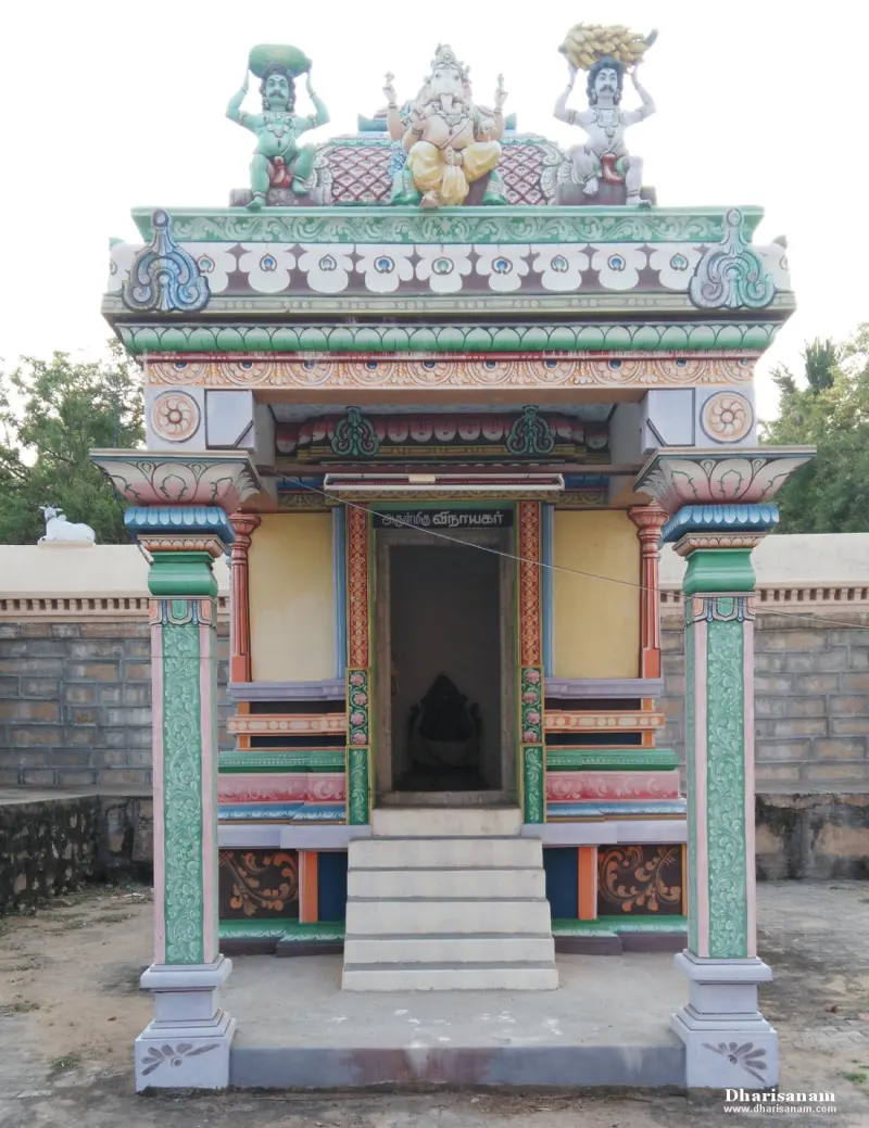 Small brightly painted shrine with steps and a decorated roof, standing before the compound wall