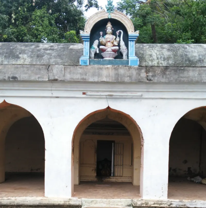 A white arched corridor with a painted seated goddess above the middle arch