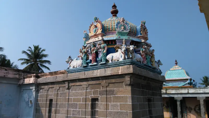 Painted shrine tower with white bulls and standing figures above a stone wall