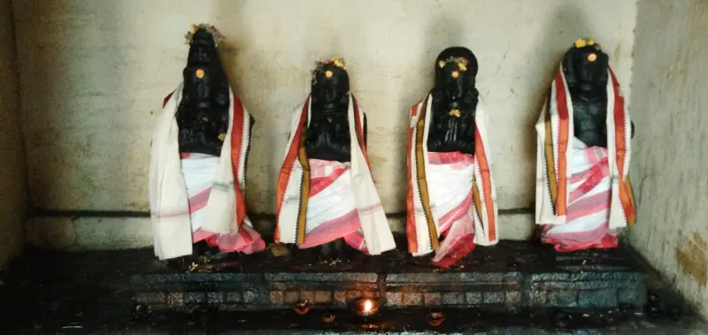 Four draped black saints with folded hands in a niche