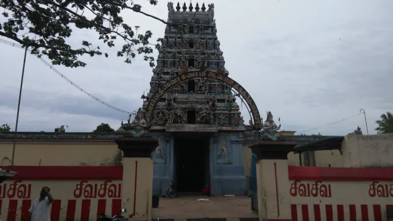 Front view of the entrance tower with an arched name board, and red and cream walls with Tamil lettering.