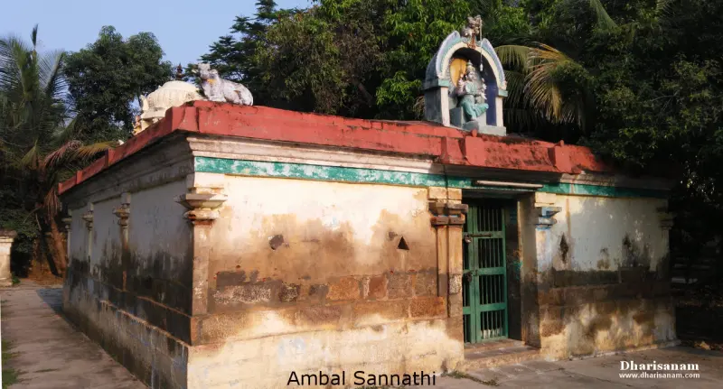 A shrine hall with a red roof, Nandhi on top, and a goddess above the door