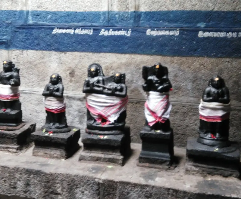 Black stone saints draped in cloth, the middle pair holding a staff