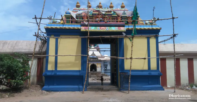 A blue and yellow gateway with painted figures on top, wrapped in bamboo scaffolding, and a temple roof seen beyond